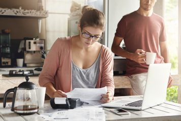 Spouses looking at bills together at home in the morning