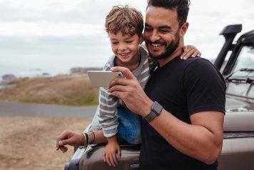Father and Son Outside Using Smartphone App