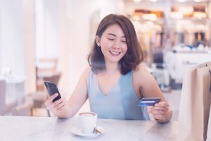 A woman looks at her credit card while using card control on her mobile phone.