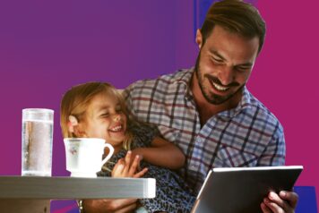 Father and Daughter at Home Laughing while dad looks at Tablet Computer