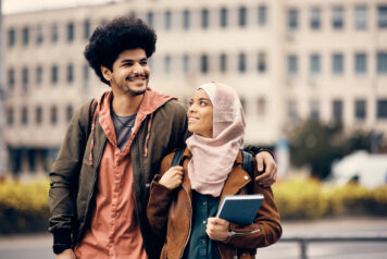 Happy Middle Eastern college couple walking together at campus.