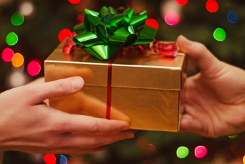 Handing a gold wrapped present to another person